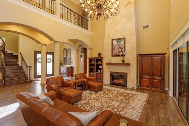 5719 Emerson Pointe Way, Orlando, FL 32819 - living room with a high end fireplace, dark wood finished floors, decorative columns, and a towering ceiling