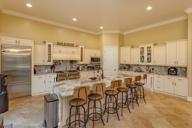 5719 Emerson Pointe Way, Orlando, FL 32819 - kitchen featuring light stone counters, high end appliances, a center island with sink, and glass insert cabinets