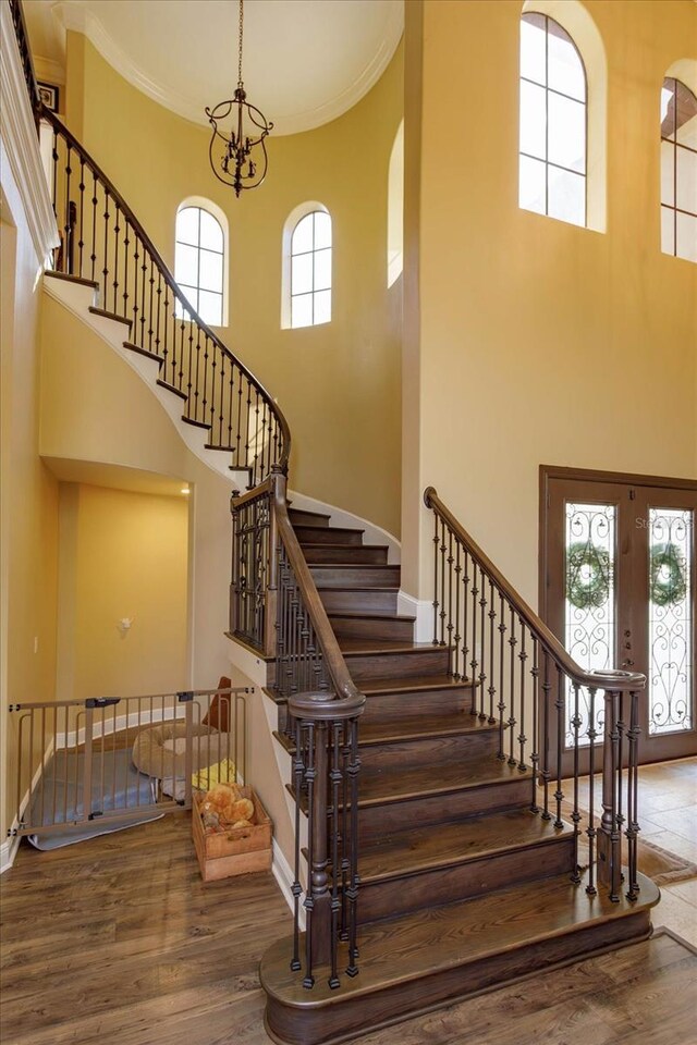 5719 Emerson Pointe Way, Orlando, FL 32819 - stairway with a chandelier, wood finished floors, a towering ceiling, baseboards, and ornamental molding