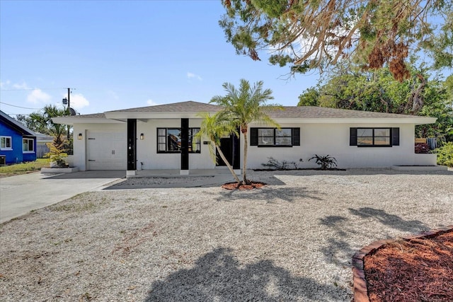 ranch-style house with concrete driveway, an attached garage, and stucco siding