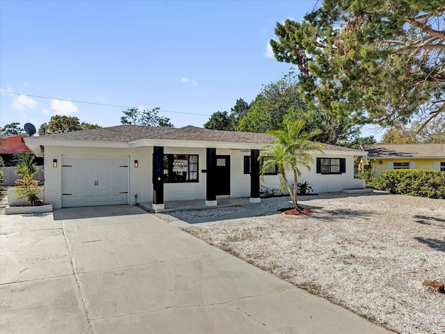 single story home with a garage, concrete driveway, roof with shingles, and stucco siding