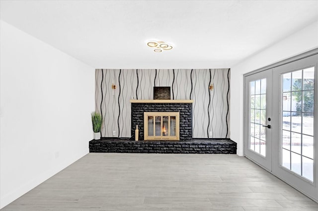 unfurnished living room with french doors, a fireplace, and wood finished floors