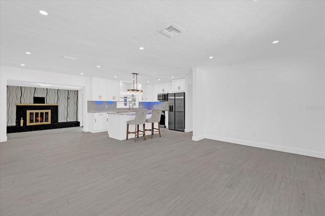 kitchen featuring open floor plan, stainless steel appliances, light countertops, a kitchen bar, and white cabinetry