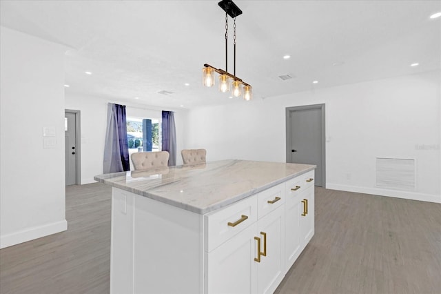 kitchen with a kitchen island, visible vents, white cabinets, light wood-type flooring, and decorative light fixtures