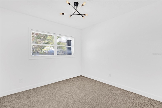 unfurnished room with carpet floors, baseboards, and a notable chandelier