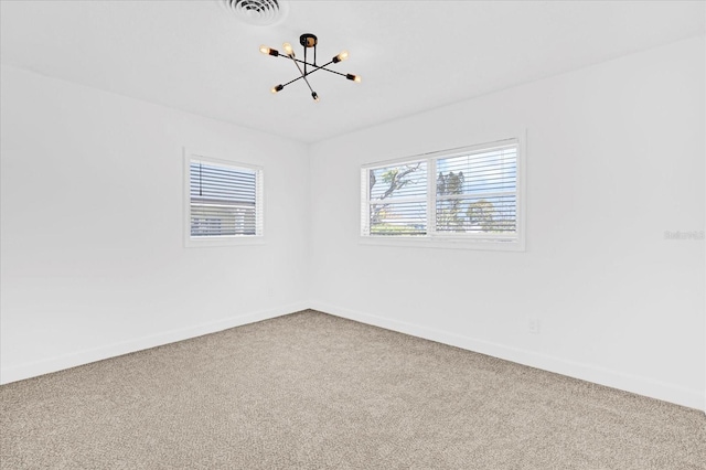 carpeted spare room featuring visible vents, baseboards, and an inviting chandelier