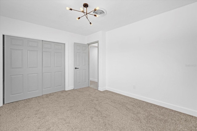 unfurnished bedroom with an inviting chandelier, carpet, baseboards, and a closet