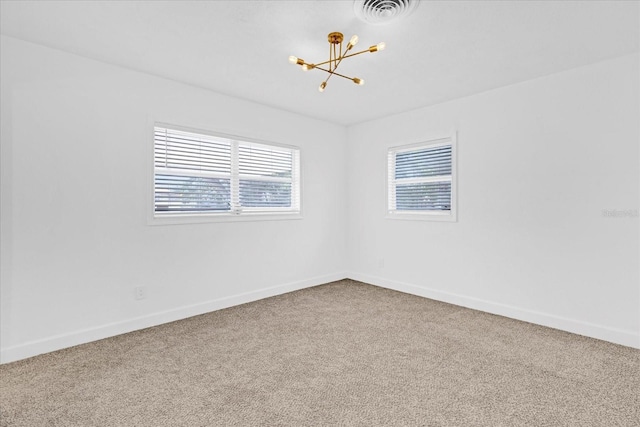 empty room with a chandelier, baseboards, visible vents, and carpet flooring