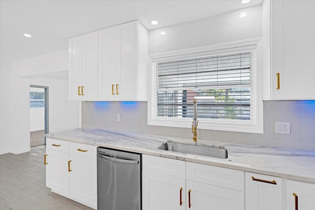 kitchen featuring stainless steel dishwasher, a sink, a wealth of natural light, and white cabinetry