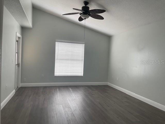 empty room with vaulted ceiling, ceiling fan, dark wood-type flooring, and baseboards