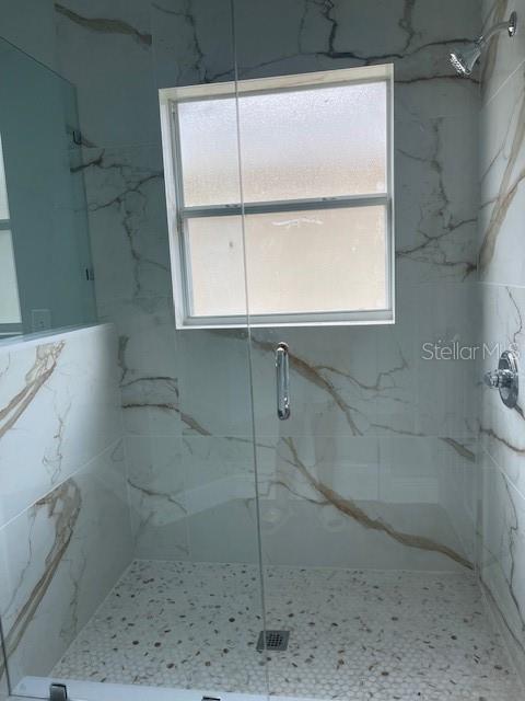 bathroom with a marble finish shower and a wealth of natural light