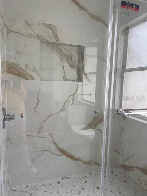 full bathroom with a marble finish shower