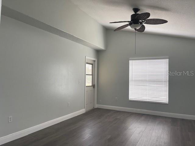 unfurnished room featuring baseboards, a ceiling fan, dark wood-style flooring, vaulted ceiling, and a textured ceiling