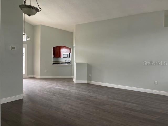 unfurnished living room featuring dark wood-type flooring and baseboards