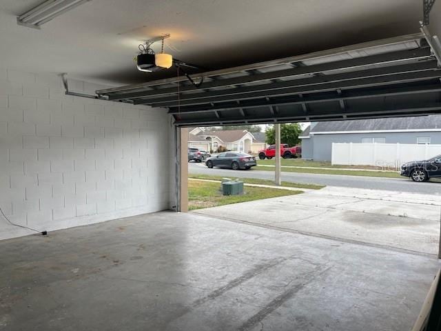 garage featuring concrete block wall and a garage door opener