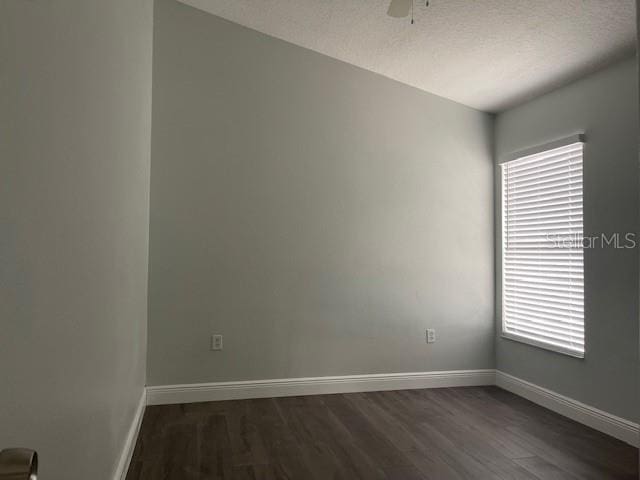 empty room with dark wood-type flooring, a textured ceiling, baseboards, and a ceiling fan