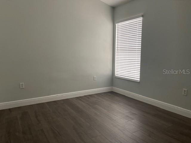 empty room featuring dark wood-style flooring and baseboards