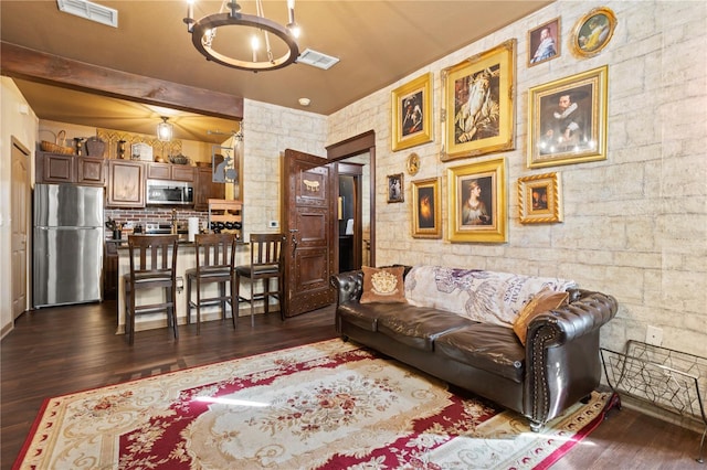 living room featuring dark wood-style floors, visible vents, beamed ceiling, and an inviting chandelier