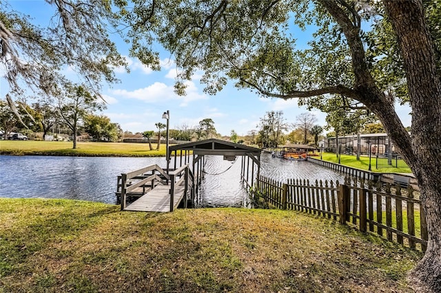 view of dock with a lawn, a water view, and fence