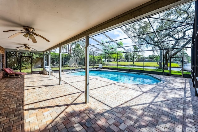 pool with a ceiling fan, a patio area, glass enclosure, and a lawn