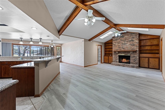 kitchen featuring a sink, lofted ceiling with skylight, open floor plan, and a textured ceiling