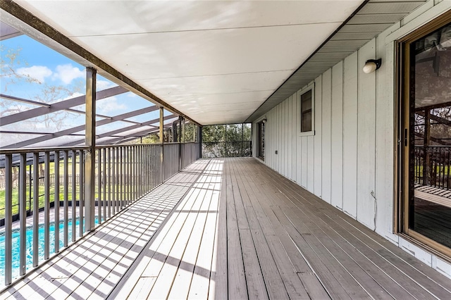 wooden terrace featuring glass enclosure and an outdoor pool