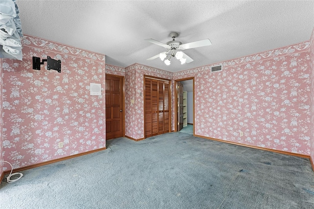 unfurnished bedroom featuring visible vents, a textured ceiling, baseboards, and wallpapered walls