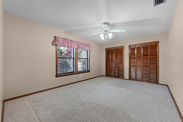 unfurnished bedroom with carpet, visible vents, and two closets