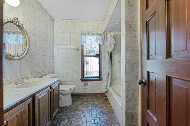 bathroom featuring tile walls, vanity, toilet, and shower / tub combo with curtain