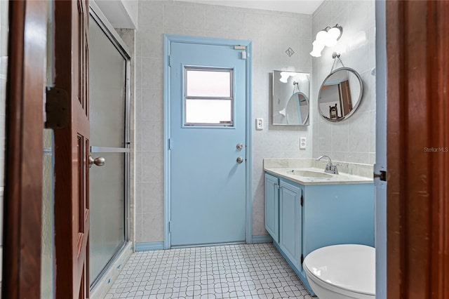 bathroom featuring a stall shower, toilet, tile walls, and vanity