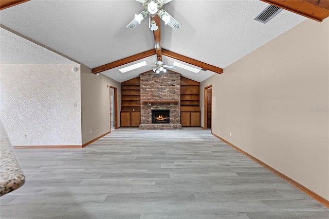 unfurnished living room with baseboards, vaulted ceiling with skylight, visible vents, and a ceiling fan