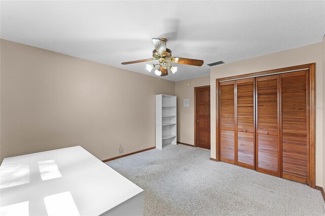 unfurnished bedroom featuring a closet, visible vents, light carpet, ceiling fan, and baseboards