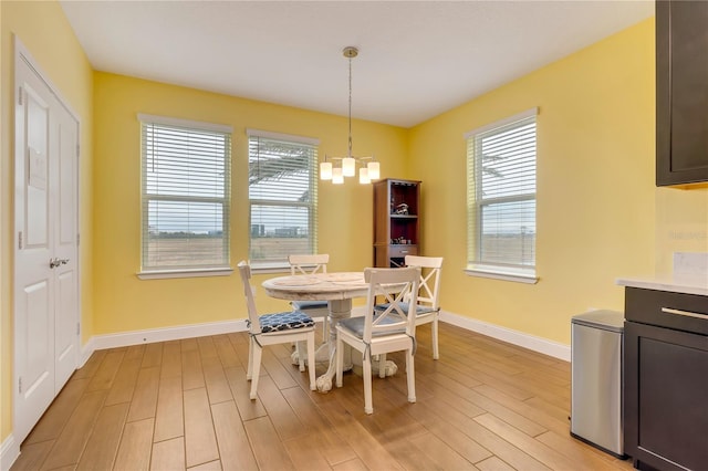 dining room with a chandelier, light wood-type flooring, and baseboards