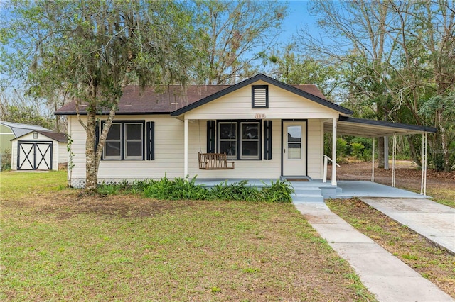 view of front facade with driveway, covered porch, a storage unit, an outdoor structure, and a carport