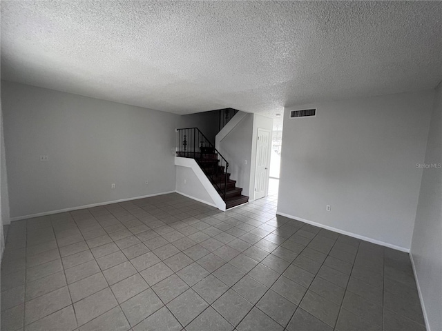 spare room featuring visible vents, stairway, baseboards, and dark tile patterned floors