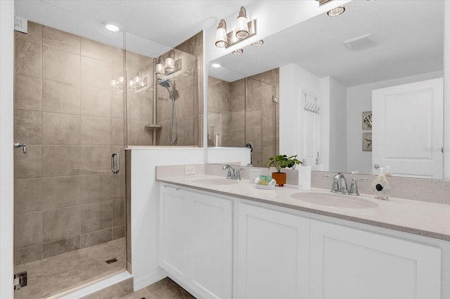 bathroom featuring double vanity, a stall shower, and a sink