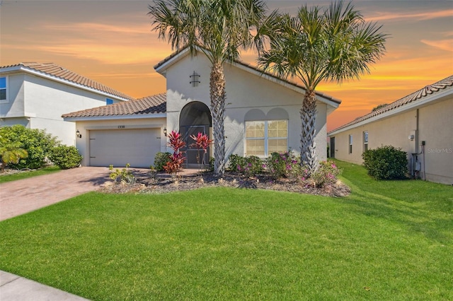 mediterranean / spanish-style house with a garage, driveway, a front lawn, and stucco siding