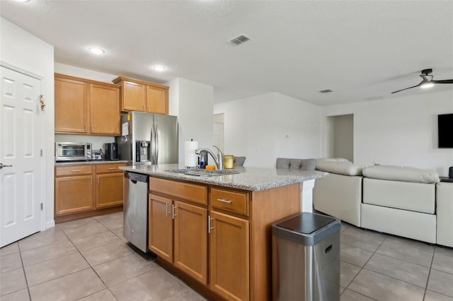 kitchen with light tile patterned floors, appliances with stainless steel finishes, open floor plan, and a sink