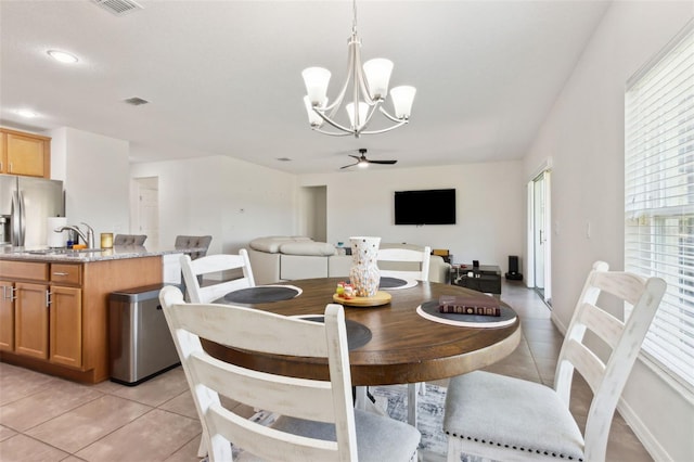 dining area featuring light tile patterned floors, baseboards, visible vents, and ceiling fan with notable chandelier