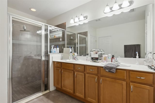 bathroom with double vanity, a shower stall, a sink, and tile patterned floors