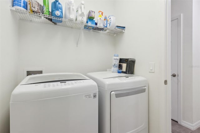 washroom with laundry area, washer and clothes dryer, and baseboards