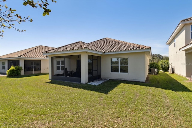 back of house with a yard, a tiled roof, a sunroom, and central air condition unit