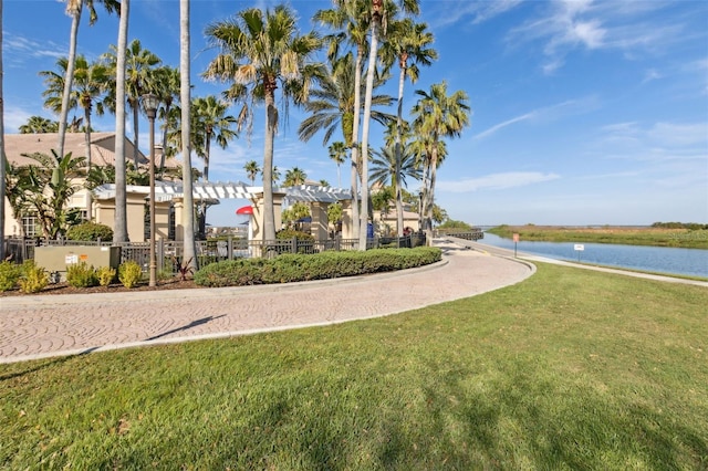 view of community featuring a lawn, a water view, and fence