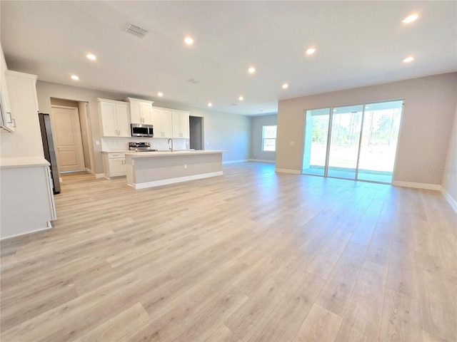 unfurnished living room featuring light wood-type flooring, baseboards, visible vents, and recessed lighting