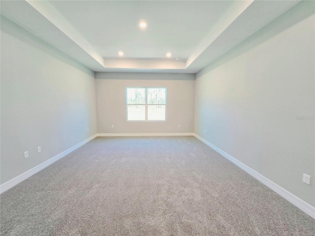 spare room featuring carpet floors, a tray ceiling, recessed lighting, and baseboards