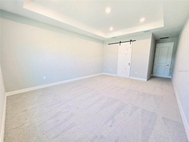 unfurnished bedroom with recessed lighting, a raised ceiling, visible vents, a barn door, and baseboards