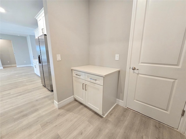 hallway with light wood-type flooring and baseboards