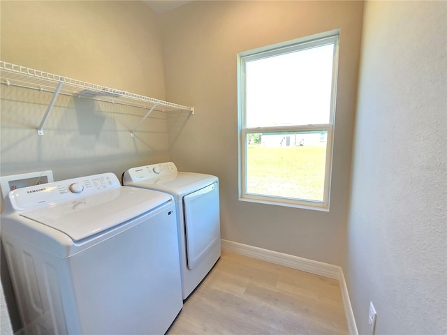 laundry area with light wood-type flooring, laundry area, baseboards, and washing machine and clothes dryer