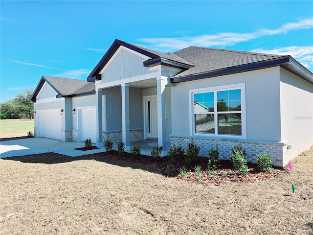 view of front of home with an attached garage, brick siding, driveway, roof with shingles, and stucco siding