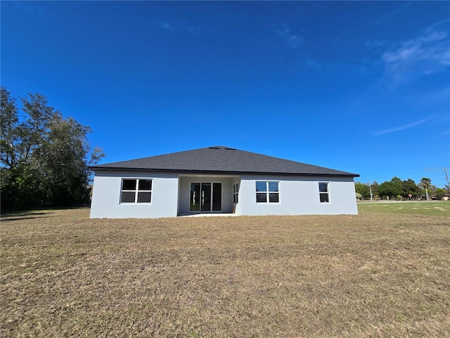 back of house with a yard and stucco siding